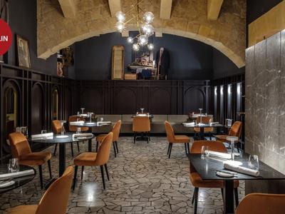 Modern eingerichtetes, elegantes Restaurant mit rundlichen Tischen und komfortablen Stühlen unter einem Steinbalken-Gewölbe.