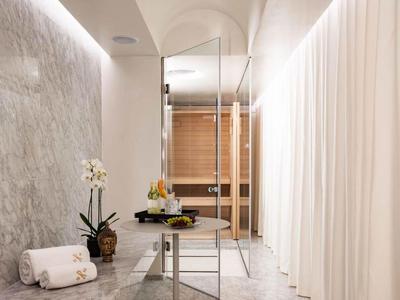 Moderner Wellnessbereich mit Tisch, Obst und Handtüchern vor Saunatür und Vorhangwand.