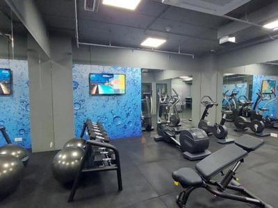 Gimnasio moderno con equipos de ejercicio y grandes espejos en las paredes.