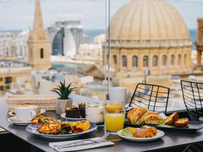 Desayuno en mesa con vista a ciudad y edificios históricos en día despejado.