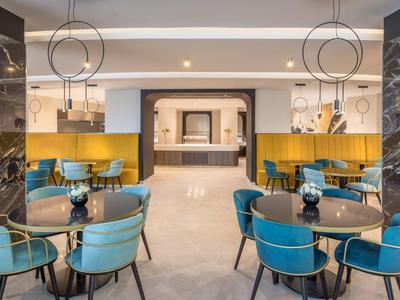 Hall d'hôtel moderne avec des fauteuils bleus, des tables et un éclairage élégant.