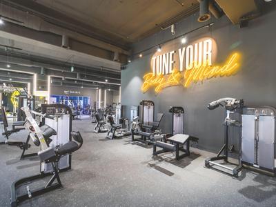 Gimnasio moderno con varias máquinas de entrenamiento y una cita motivadora en la pared.