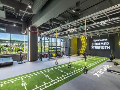 Gimnasio moderno con pista verde y bandas TRX en un hotel.