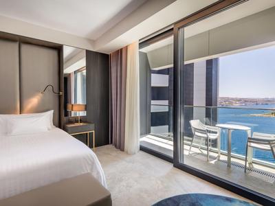 Chambre d'hôtel moderne avec lit double et balcon avec vue sur la mer.