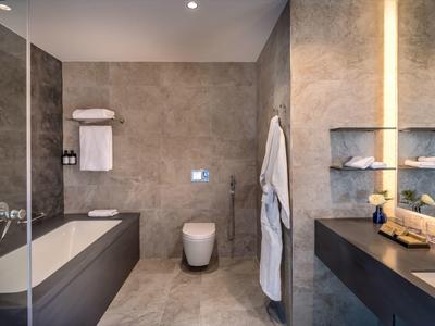 Salle de bain moderne avec baignoire, toilettes, lavabo et miroir éclairé.