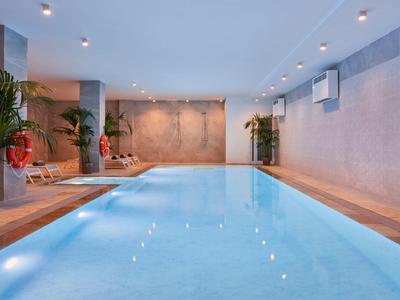 Piscine intérieure moderne avec terrasse en bois et plantes dans un cadre élégant.