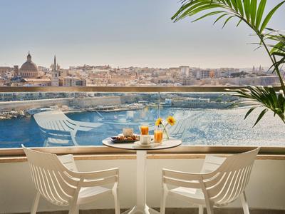 Balcon avec deux chaises et table de petit déjeuner avec vue sur la ville et l'eau