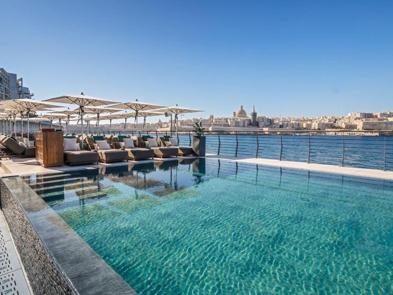 Piscine à débordement avec vue sur la ville et la mer par temps clair