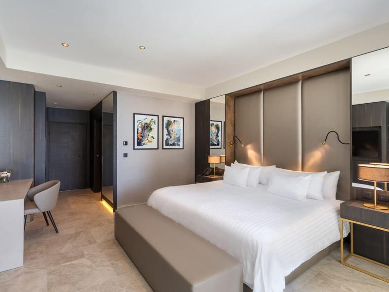 Chambre d'hôtel moderne avec lit double, bureau, œuvres murales et lampes de chevet.