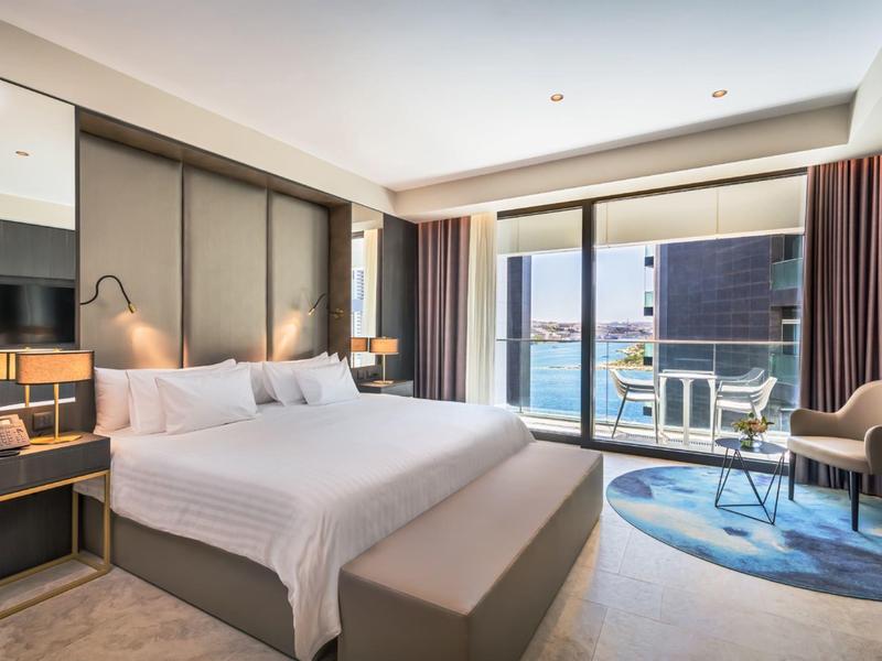 Chambre d'hôtel moderne avec grand lit, balcon et vue sur la mer