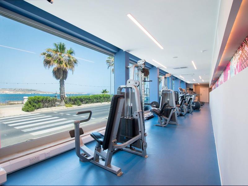 Un gimnasio moderno con equipo y grandes ventanas con vista al mar.