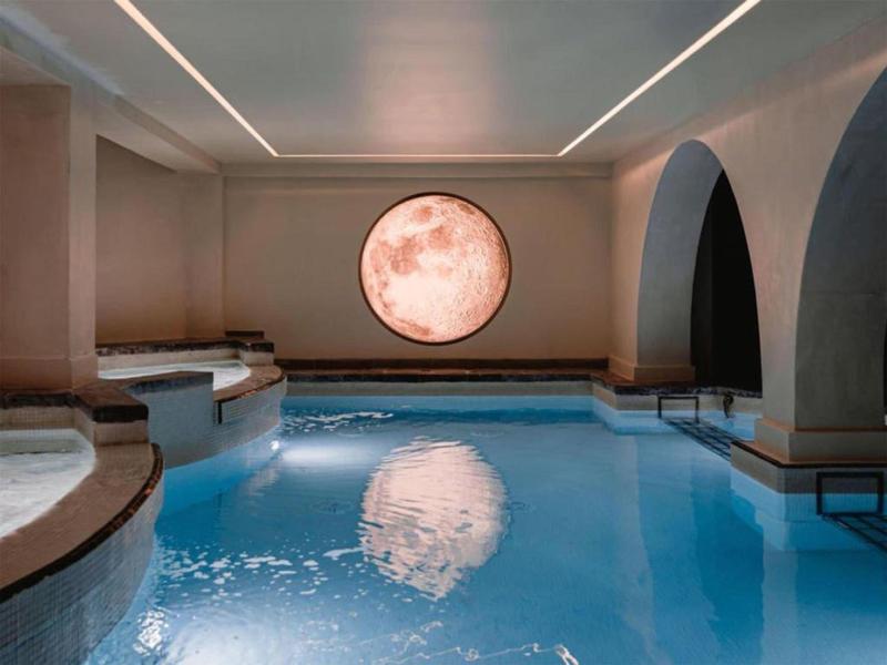 Piscina cubierta moderna con ventana redonda y tumbonas relajantes.