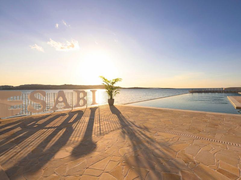 Terraza soleada con piscina y vistas al agua al amanecer o al atardecer