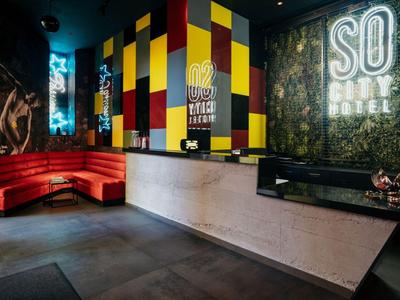 Ingresso moderno dell'hotel con elementi colorati alle pareti e divano rosso