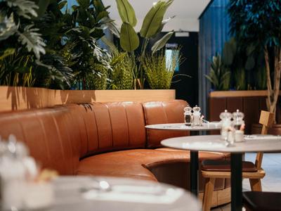 Angolo accogliente con pelle marrone e tavoli bianchi rotondi in un ristorante moderno.