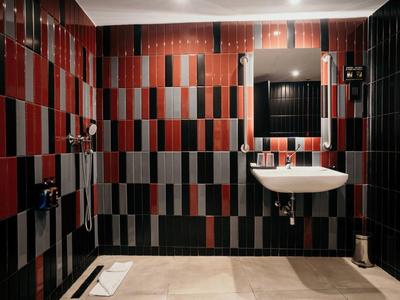 Bagno moderno con piastrelle rosse e nere alle pareti e lavabo bianco.