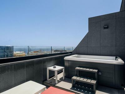 Moderna terrazza sul tetto con vasca idromassaggio e posti a sedere con vista sul mare.