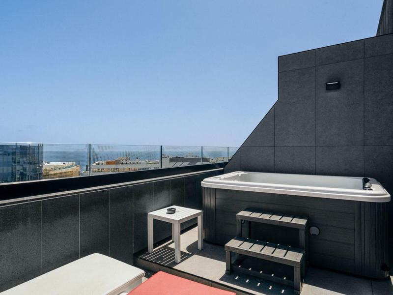 Moderna terrazza sul tetto con vasca idromassaggio e posti a sedere con vista sul mare.