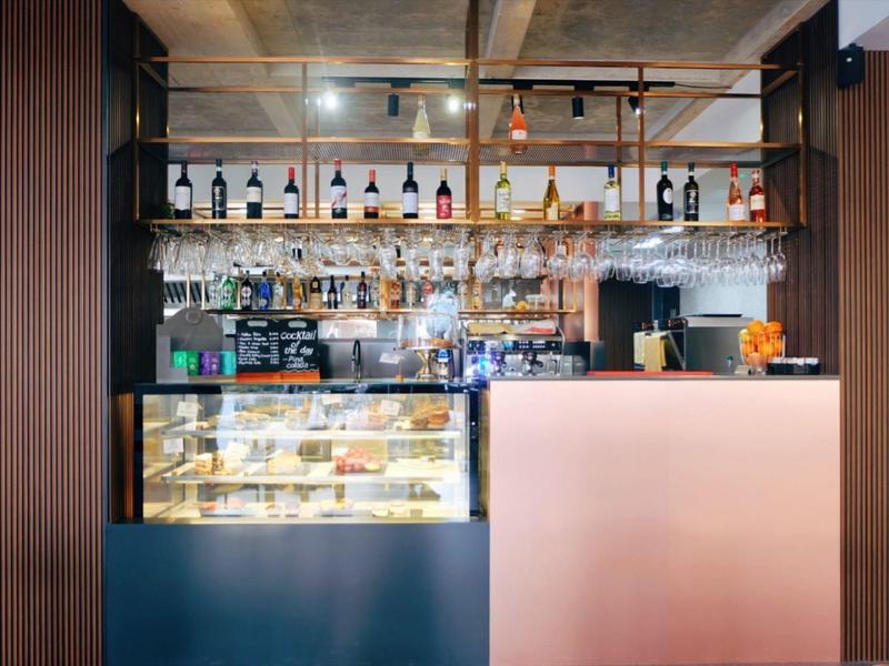 Nowoczesny bar hotelowy z podświetlaną szklaną półką i ciastami w witrynie