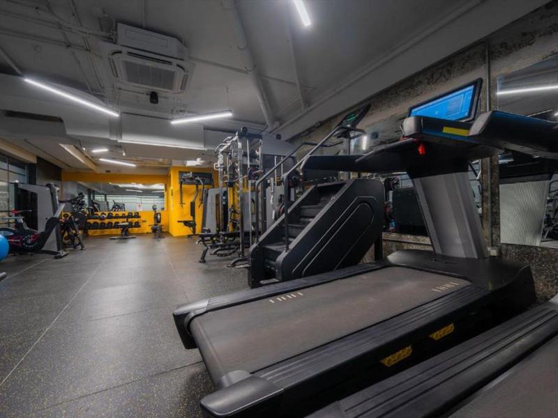Nowoczesna siłownia z bieżnią, sprzętem siłowym i lustrzanymi ścianami.