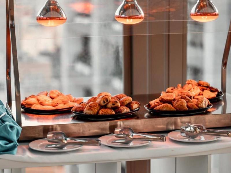 Tace z pieczywem pod lampami grzewczymi na bufecie śniadaniowym.