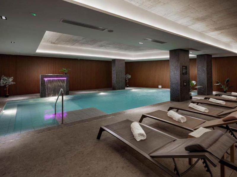 Nowoczesny basen kryty z leżakami i przyciemnionym oświetleniem w stylowej atmosferze.