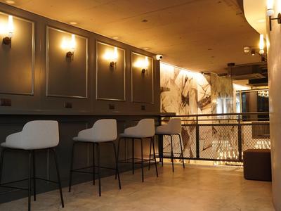 Moderner Hotelbar-Bereich mit hohen weißen Stühlen und warmem Licht.