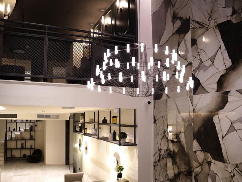 Modern hotel lobby with chandelier, black-and-white abstract wall art, and reception desk.