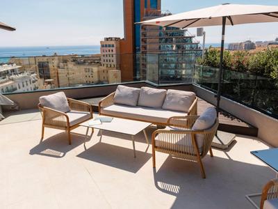 Moderne Terrasse mit Sofa, Sesseln und Blick auf Stadt und Meer.