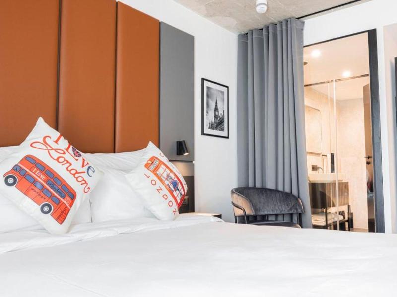 Modernes Schlafzimmer mit weißem Bett, oranger Kopfteilwand und dekorativen Kissen.