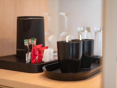 Kaffeetassen und Kaffeemaschine auf einem Tablett in einem Hotelzimmer.