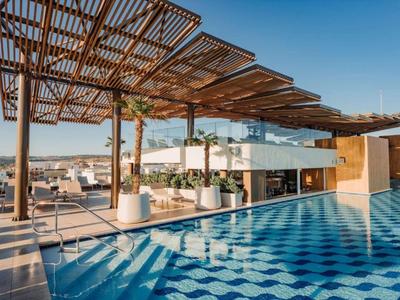 Moderner Hotelpool mit überdachtem Lounge-Bereich und Bergblick bei Sonnenuntergang.