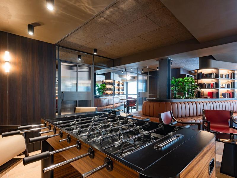 Moderne Lounge mit Kicker, gemütlichen Sitzbereichen und stilvoller Innenraumgestaltung.