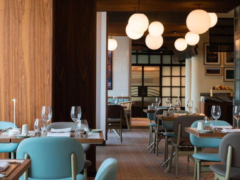 Elegantes Restaurant mit runden Lampen und türkisfarbenen Stühlen am Tisch