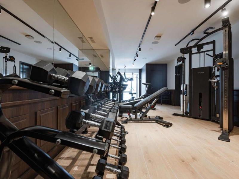 Moderner Fitnessraum mit Holzboden, Hanteln und Trainingsgeräten in einem Hotel.