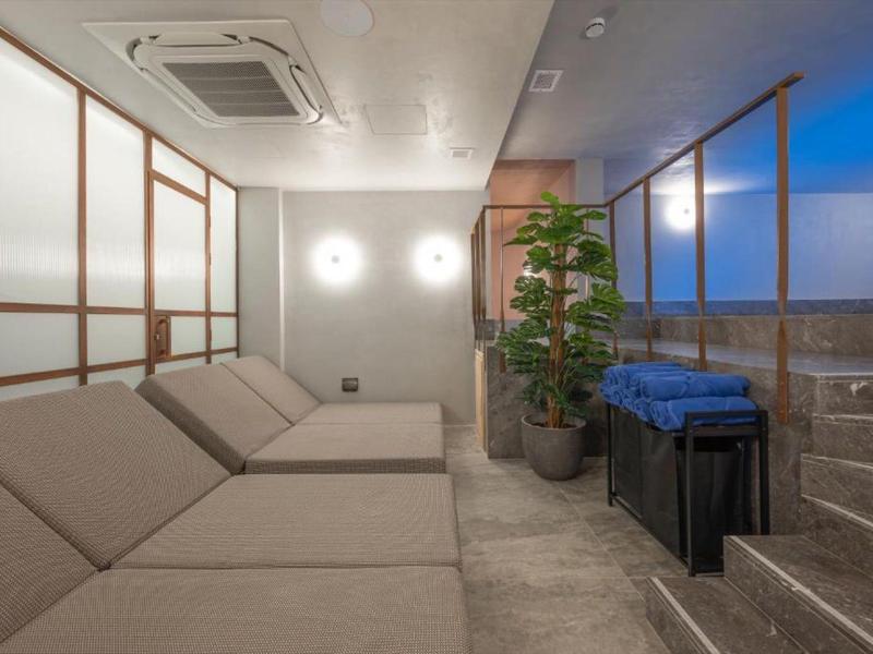 Moderner Ruheraum mit Liegen, Pflanzen und gedämpfter Beleuchtung in einem Hotel.