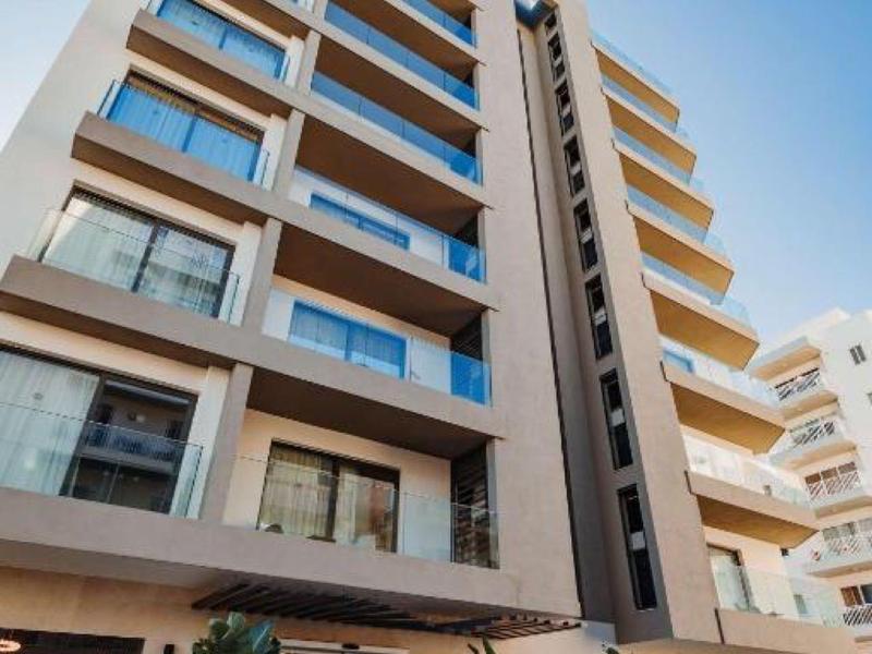 Moderner mehrstöckiger Hotelbau mit großen Fenstern und Balkonen unter klarem Himmel.