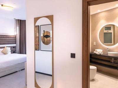 Nowoczesny pokój hotelowy z podwójnym łóżkiem i łazienką z okrągłym lustrem i umywalką.