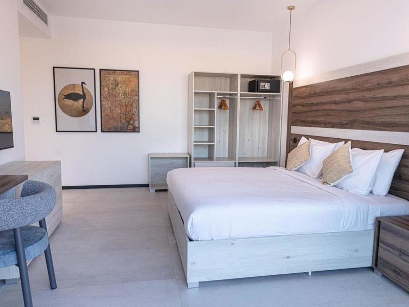 Modern hotel room with double bed, wooden accents, desk, and wall art.