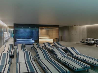 Espacio interior con tumbonas frente a un jacuzzi y una sauna en un área de bienestar.