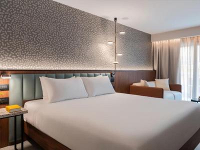 Habitación de hotel moderna con cama grande, área de sofá y suelo alfombrado.