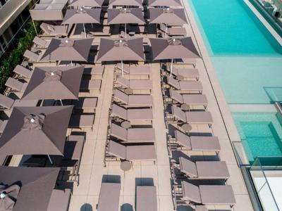 Vista aérea de una piscina con sombrillas y tumbonas en una terraza de hotel
