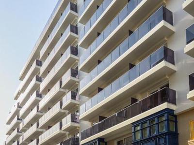 Complejo hotelero moderno con balcones y barandillas de vidrio bajo un cielo despejado.