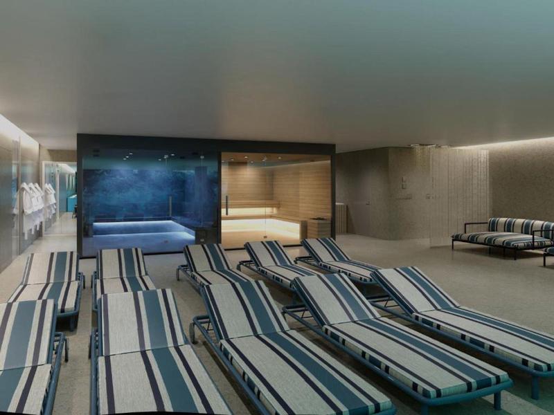 Espacio interior con tumbonas frente a un jacuzzi y una sauna en un área de bienestar.