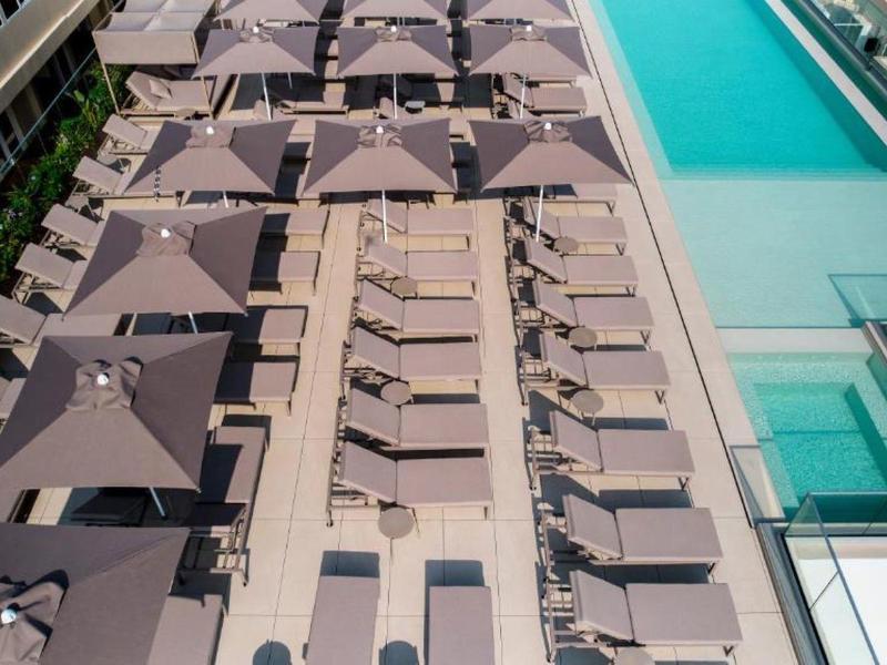 Vista aérea de una piscina con sombrillas y tumbonas en una terraza de hotel