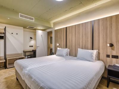 Modernes Hotelzimmer mit großem Doppelbett, Holzverkleidung und minimalistischem Design.