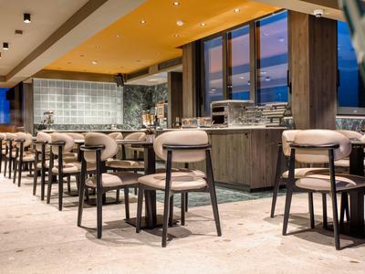 Moderner Hotelbarbereich mit hohen Hockern und Theke bei Dämmerung