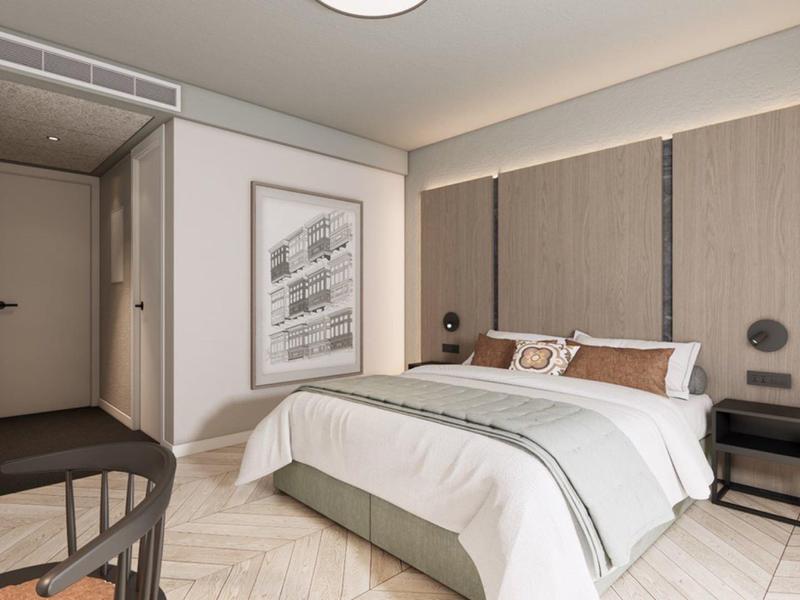 Habitación de hotel moderna con cama doble, cabeceras acolchadas grises y suelo de madera en tonos neutros.