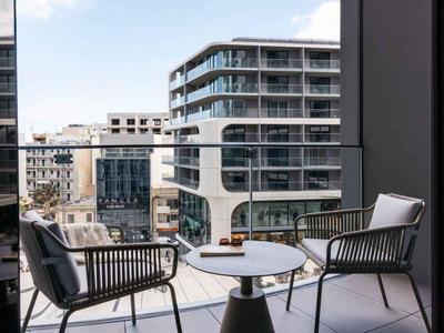 Balkon se dvěma židlemi a stolem, pohled na moderní městské bytové domy.