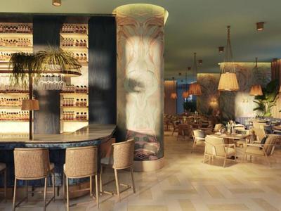 Bar elegante in hotel con bancone curvo, sedie alte, scaffali illuminati e zona salotto accogliente.